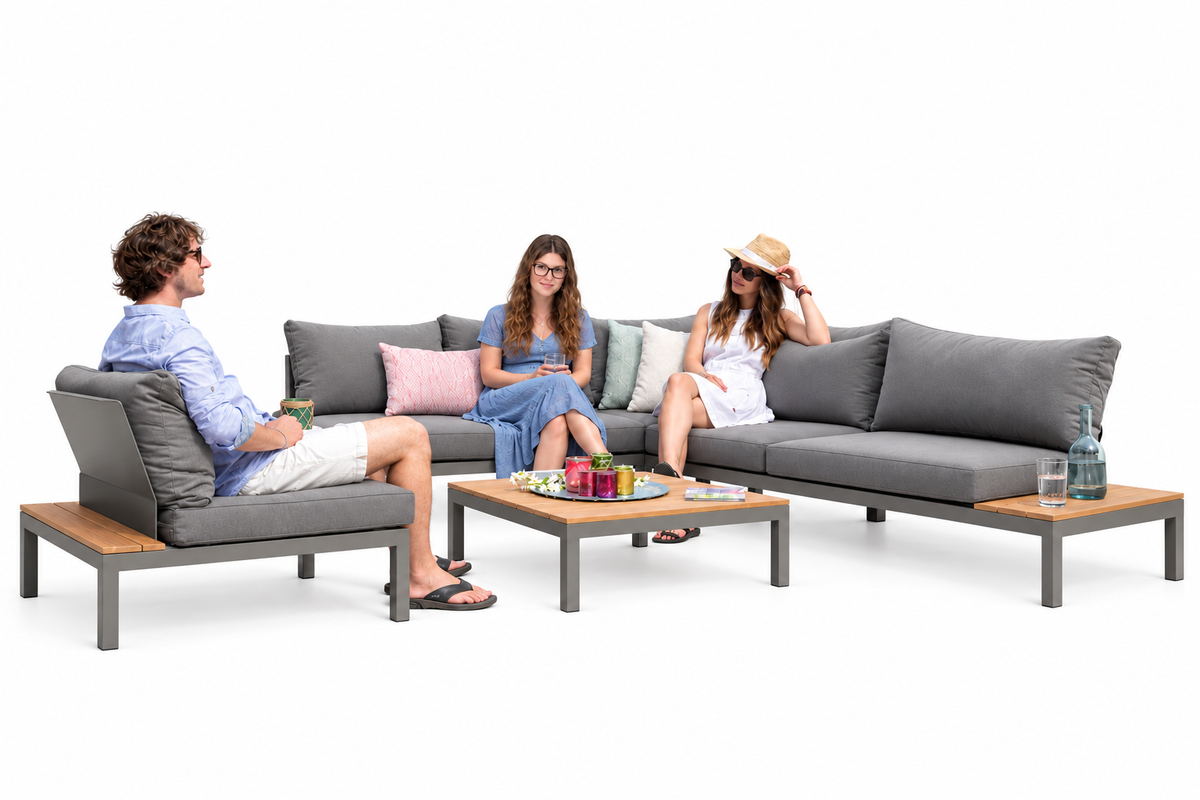 Graue Ecklounge Marlow mit Sessel und dekoriertem Couchtisch vor weissem Hintergrund. Zwei Frauen sitzen auf dem Sofa, ein Mann im Sessel.