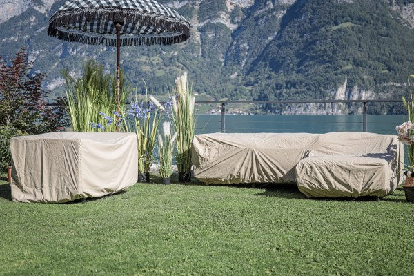 Beige Outdoor Regenschutz für Gartenmöbel auf grünem Rasen.