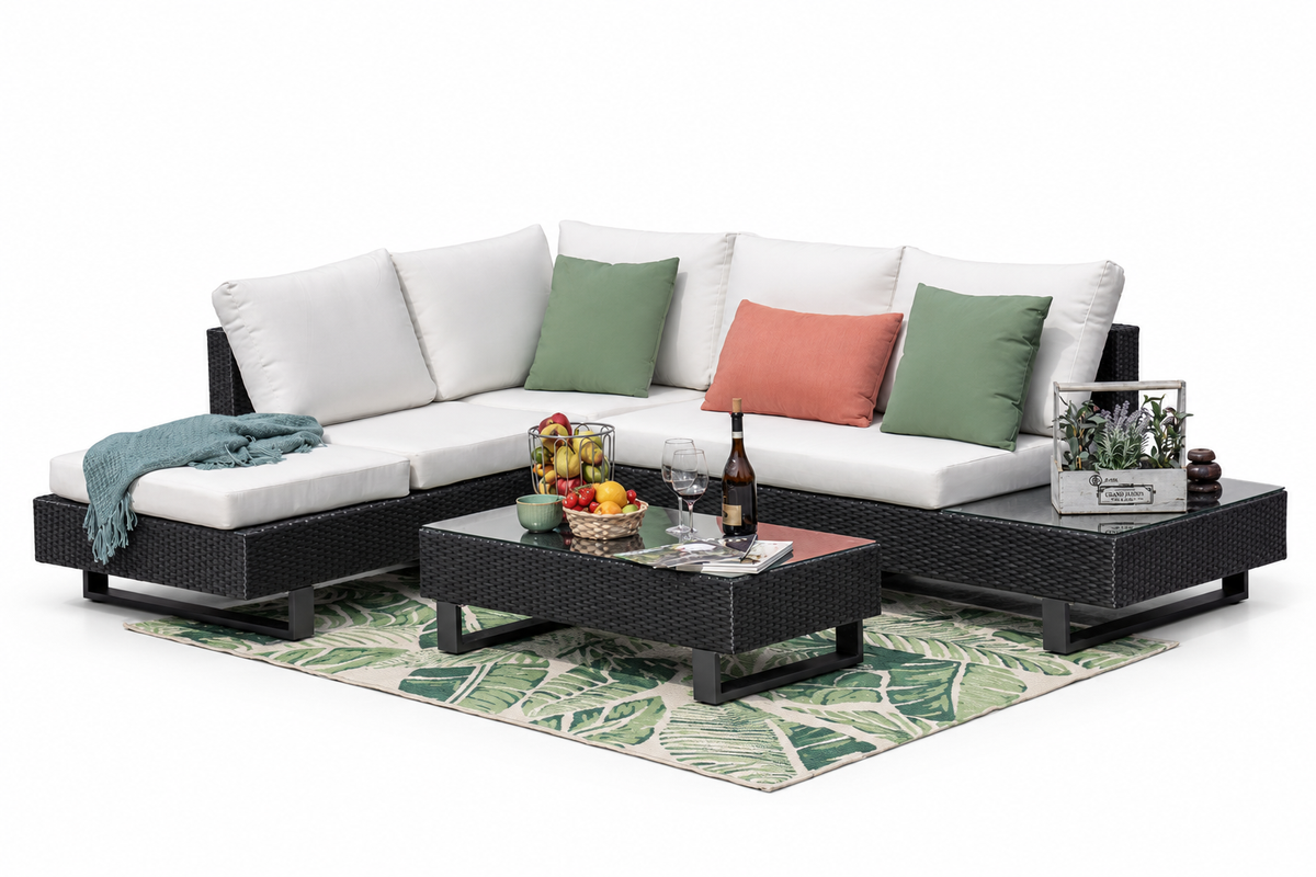 Schwarze Rattanlounge Tessa mit weissen Polstern, Loungetisch und gemustertem Teppich vor weissem Hintergrund.