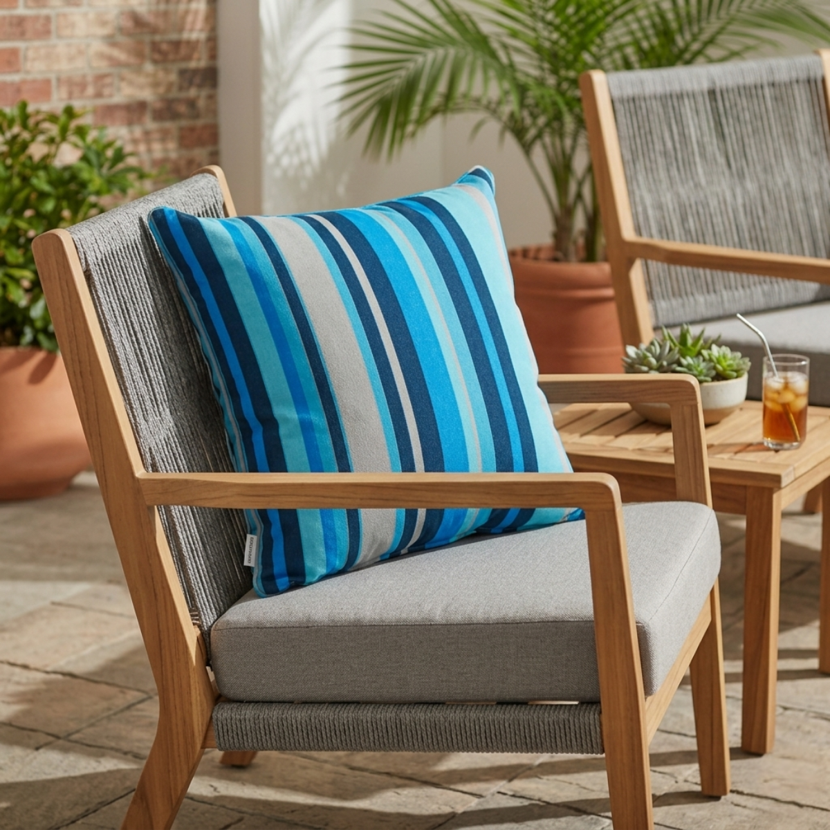 Zierkissen mit blauen Streifen für den Outdoor-Bereich auf einem Stuhl